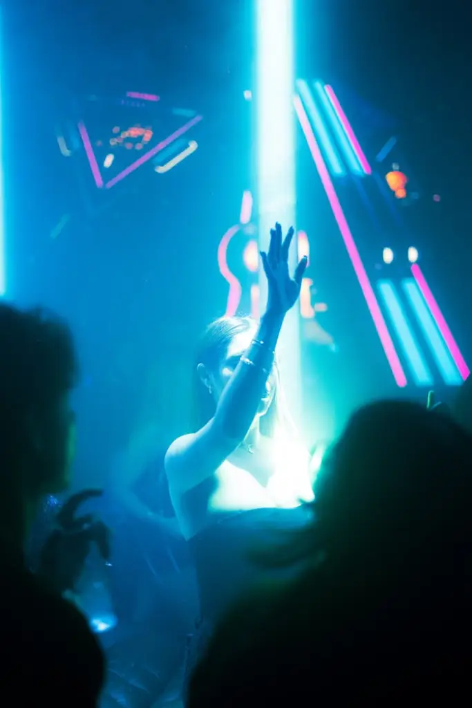 People dancing in a nightclub with glowing neon lights and energetic atmosphere.