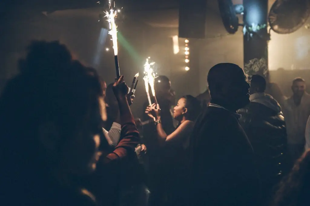 Party scene at a nightclub featuring people with sparklers and atmospheric smoke.