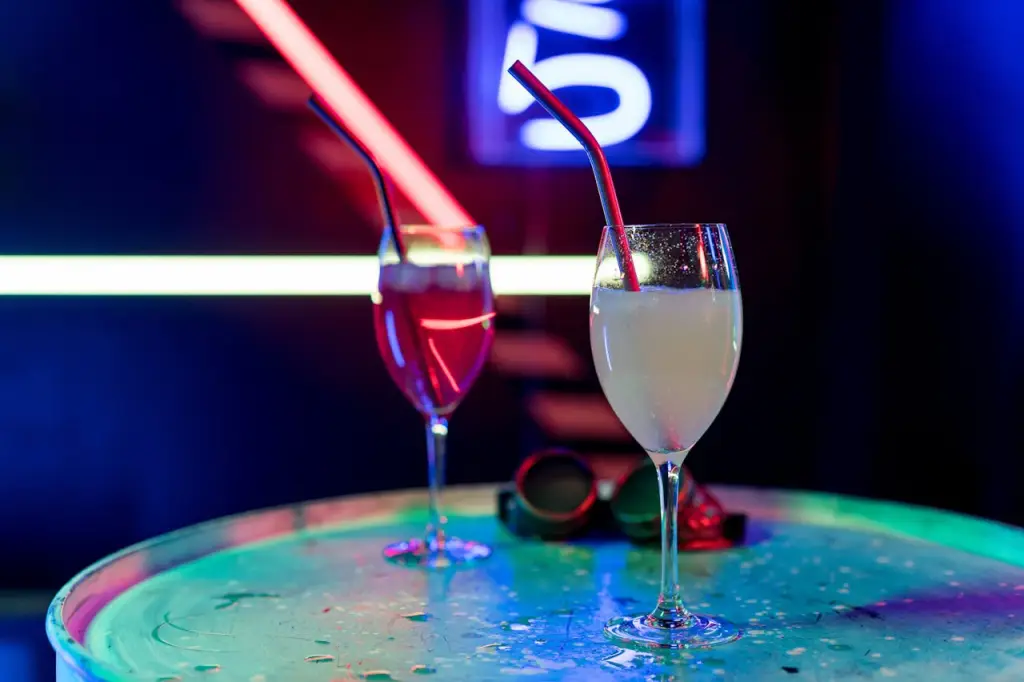 Elegant cocktails showcased on a table under vibrant neon lights, creating a lively nightlife ambiance.